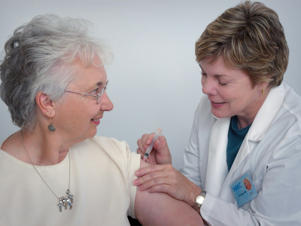 A smiling older woman chatting with a friendly care professional.